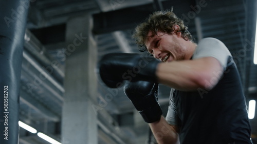 Quadro em tela Emotional fighter hitting boxing bag in fitness center