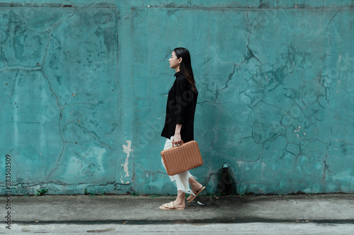 Woman with bag walking along the green wall.