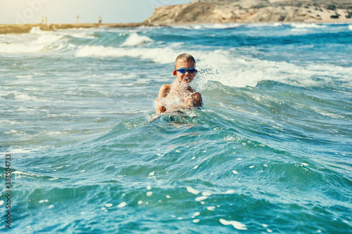 Boy in swimming glasses playing with sea waves