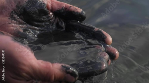 oil in human hands, oil slick, petrol pollution disaster. polluted water concept. lack of fresh drinking water for agriculture and farming. water pollution by petroleum oils photo