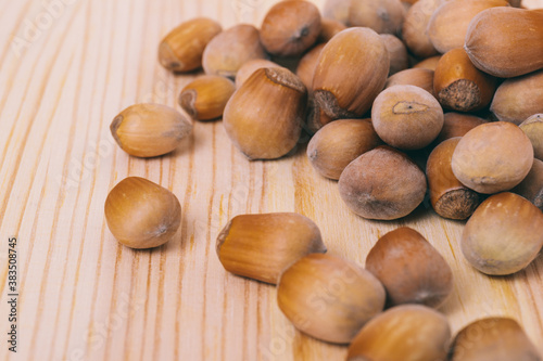 Pile of nuts. Hazelnuts. Whole nuts. Corylus avellana. Macro photo, close up, on wooden table.