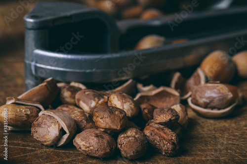 Nutcracker, whole nuts, shelled nuts and shells. Corylus avellana. Macro photo, close up, on wooden table.