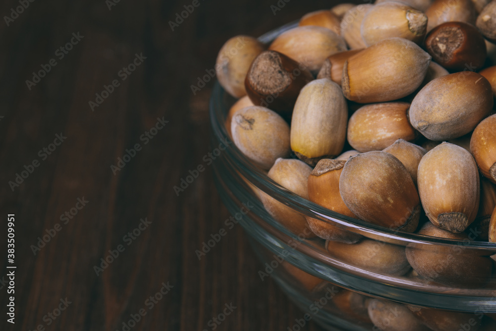 Hazelnuts in glass bowl. Whole nuts. Corylus avellana. Macro photo, close up, on wooden background. Hazelnuts in glass bowl. Whole nuts. Corylus avellana. Macro photo, close up, on wooden background.