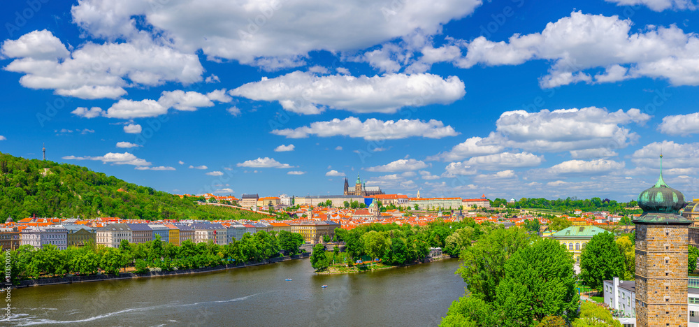 Panorama of Prague city historical centre with Prague Castle, St. Vitus Cathedral, Hradcany district, green hills and Vltava river, blue sky. Aerial panoramic view of Prague city, Czech Republic
