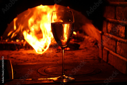  Glass of wine on the background of the hearth .