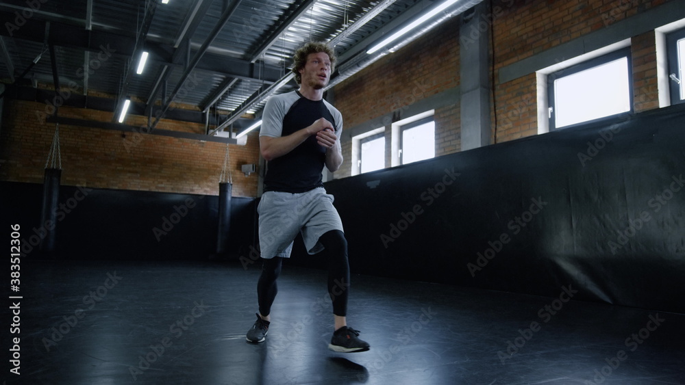 Young kickboxer doing lunges at gym. Sportsman making exercises in sport club Young kickboxer doing lunges at gym. Sportsman making exercises in sport club