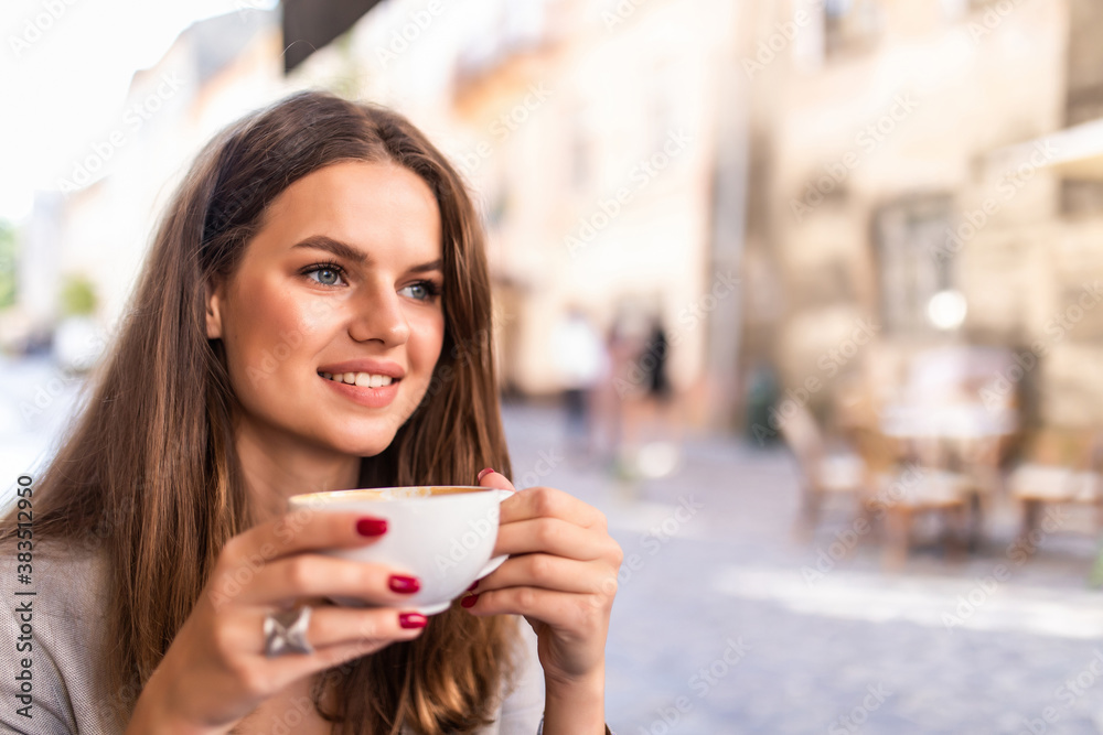 Portrait of a young woman enjoying coffee sitting outdoors at cafe during the morning Portrait of a young woman enjoying coffee sitting outdoors at cafe during the morning