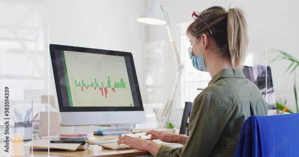 Woman wearing face mask using computer at office Woman wearing face mask using computer at office