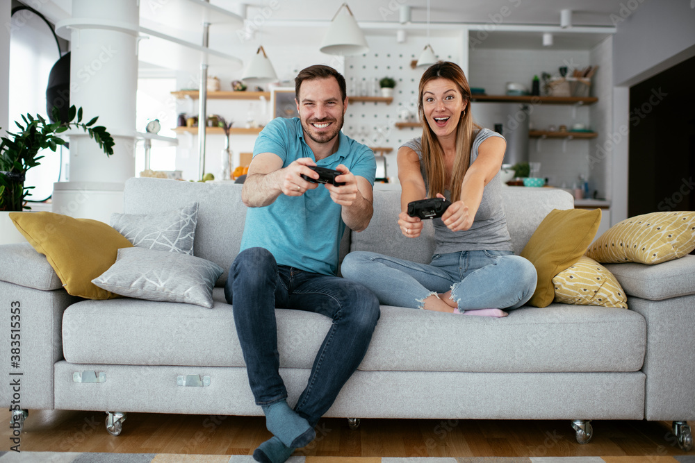 Husband and wife playing video game with joysticks in living room. Loving couple are playing video games at home. Husband and wife playing video game with joysticks in living room. Loving couple are playing video games at home.
