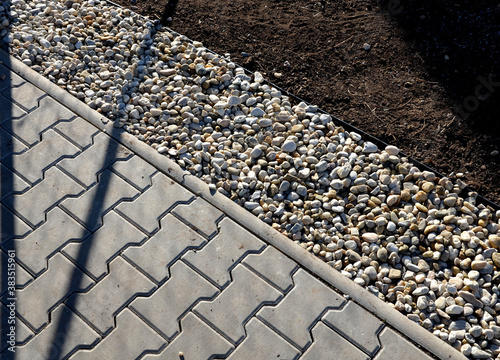 delivery of gray river pebbles like mulch to flower beds in the garden using a wheelbarow from the body of a truck or trailer. shovel and rake the layer over the black nonwoven fabric. photo