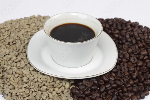 Black coffee is served in a glass cup, which is placed on top of the coffee beans. There are coffee beans that have been roasted and are still fresh beans.
