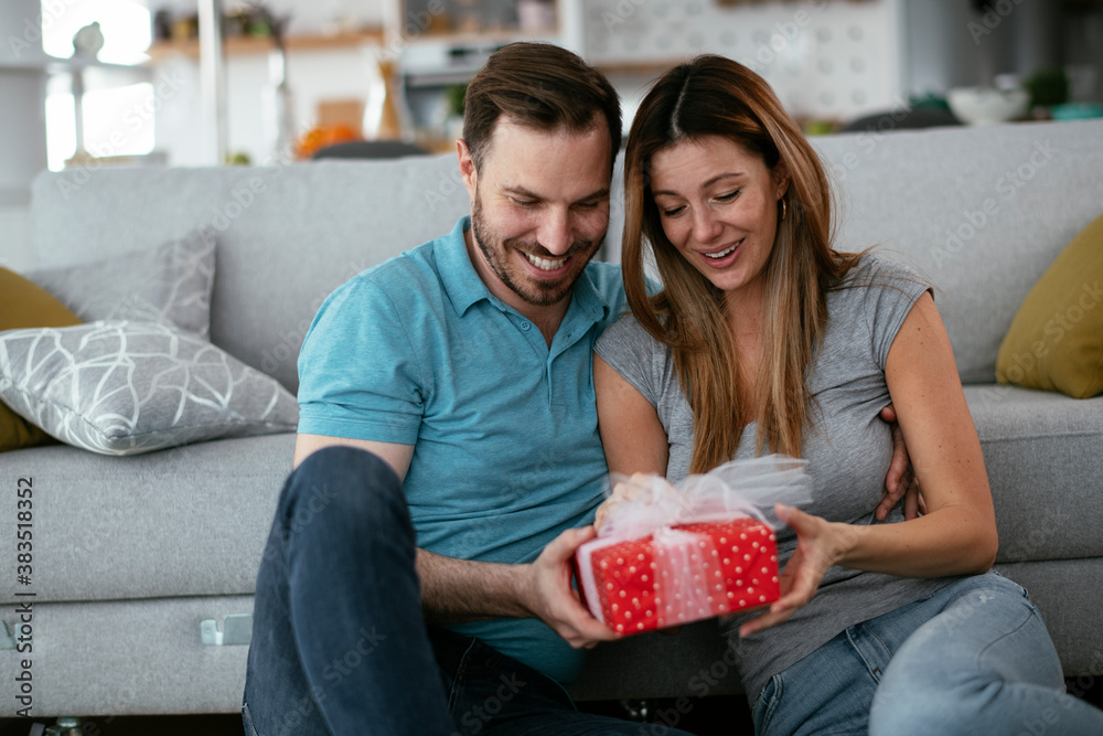 Boyfriend surprising his girlfriend with a gift. Young man giving gift box to his wife.. Boyfriend surprising his girlfriend with a gift. Young man giving gift box to his wife..