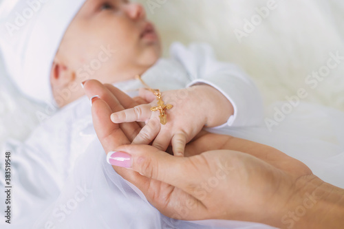 The sacrament of the baptism of a child. The kid is holding a cross. Selective focus. photo