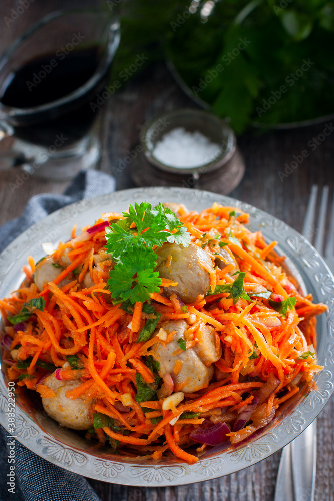 Spicy salad with champignons and Korean carrots in a metal vase, selective focus Spicy salad with champignons and Korean carrots in a metal vase, selective focus