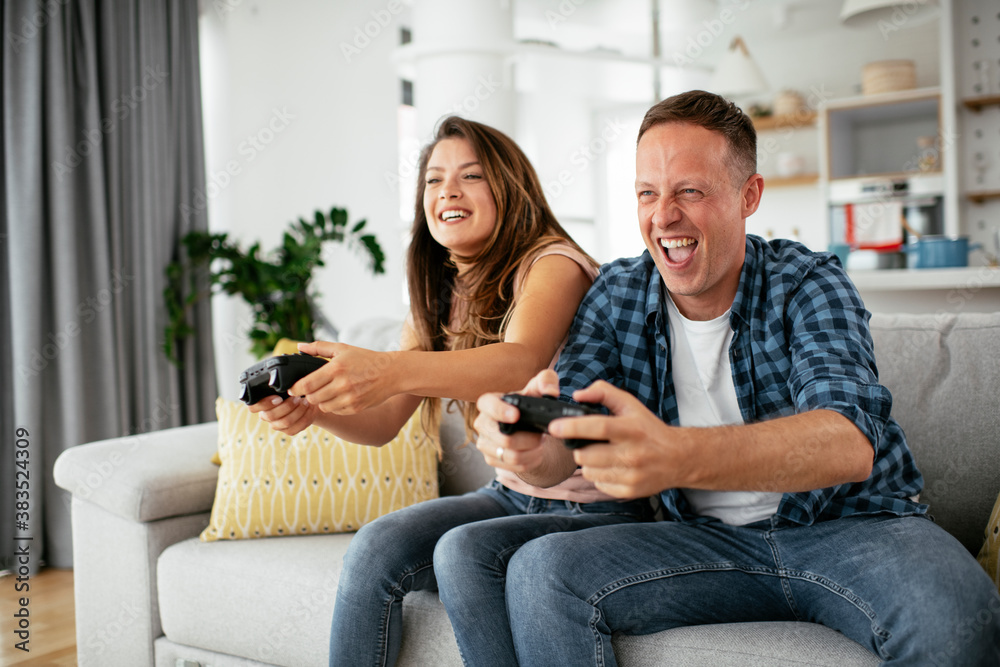 Husband and wife playing video game with joysticks in living room. Loving couple are playing video games at home. Husband and wife playing video game with joysticks in living room. Loving couple are playing video games at home.