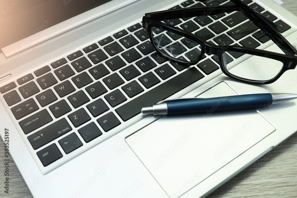 View from above on eyeglasses and pen on the laptop keyboard View from above on eyeglasses and pen on the laptop keyboard