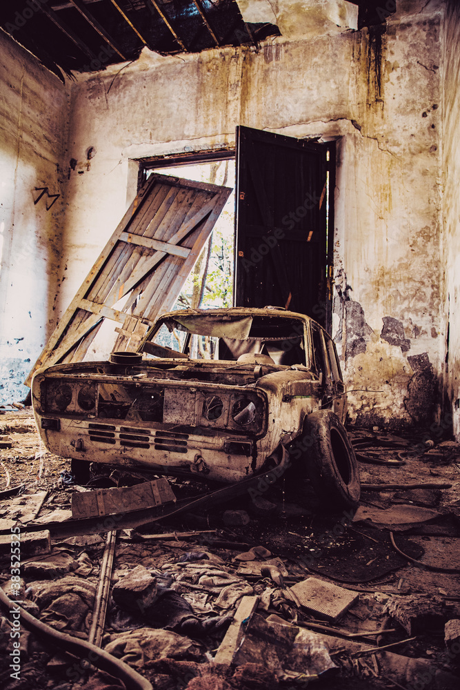 Viejo garaje con puertas de madera rota y coche abandonado