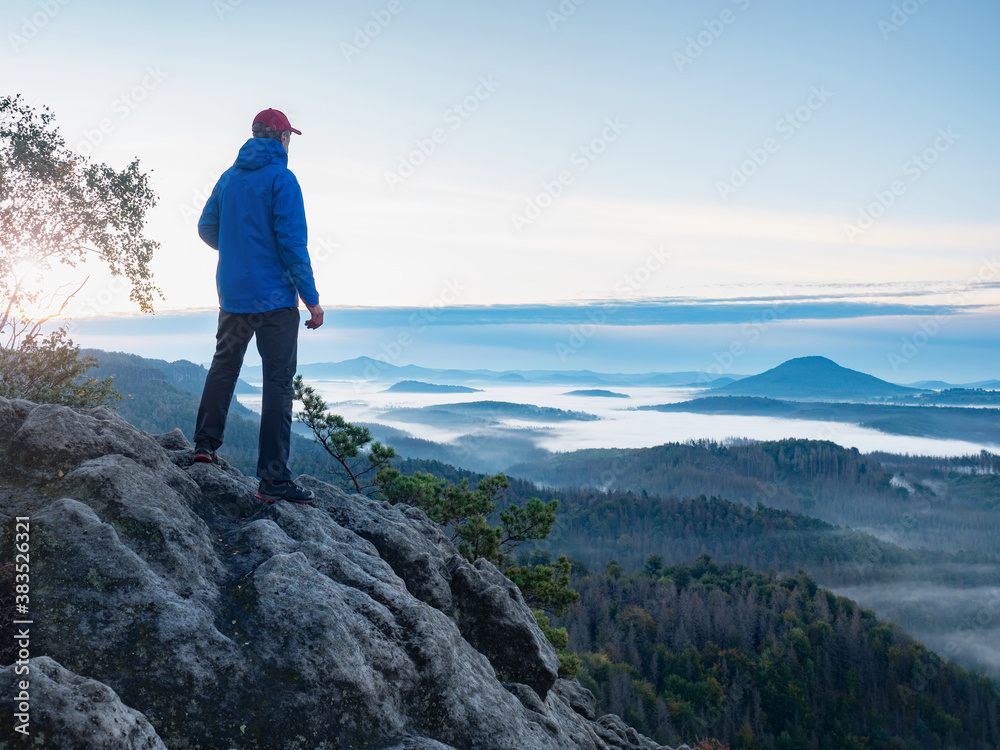 Man on the mountain peak looking on mountain valley