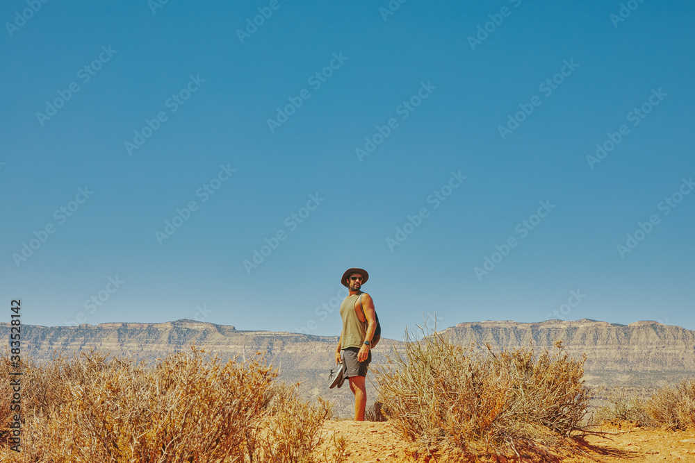 Back of young man wearing hat gazing out to desert during hike. Back of young man wearing hat gazing out to desert during hike.