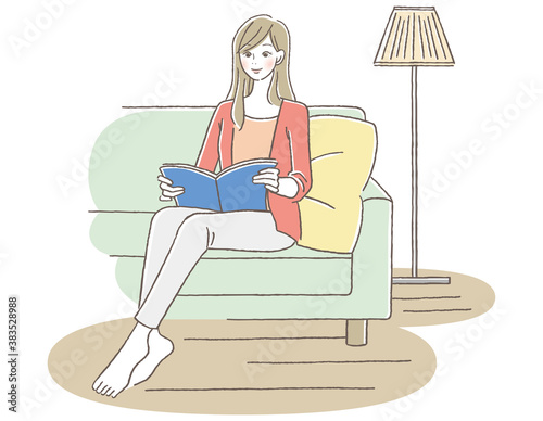 本を読みながらソファで寛ぐ女性