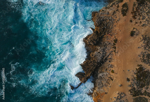 Aerial top view of sea waves hitting rocks on the beach with turquoise photo
