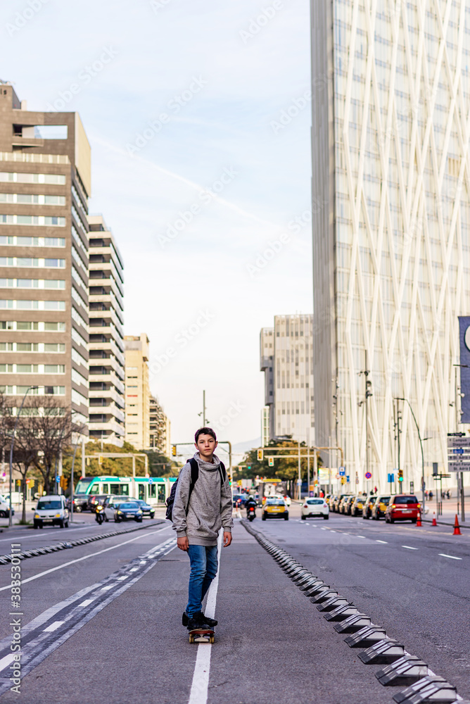 Front view of a young teen with backpack skateboarding in city street Front view of a young teen with backpack skateboarding in city street