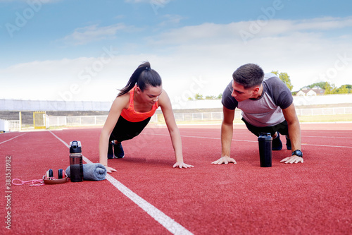 Young man and a young girl are training on the outdoor track