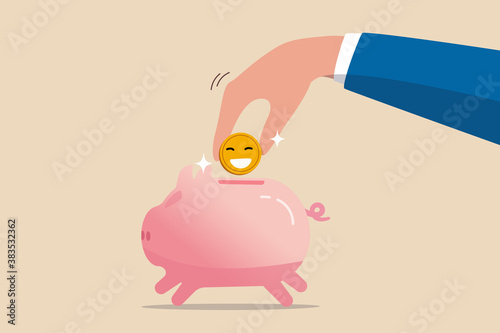 Money to buy happiness, saving for happy retirement or pay for happy lifestyle concept, hand holding golden shiny coin with happy smiling face put in pink piggy bank.