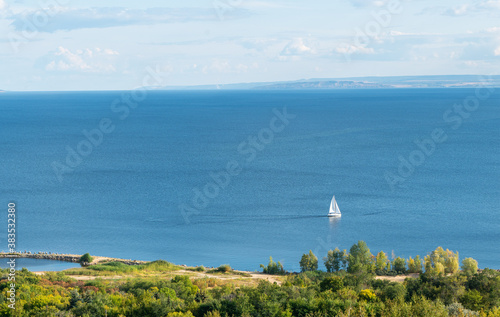 top view a yacht with white sails sails on the sea near the seashore