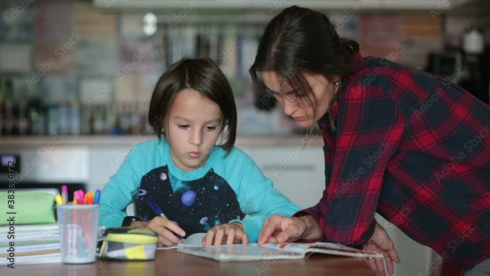 Mother, helping her child with homeworks, kid learning at home during pandemic Covid 19 lockdown Mother, helping her child with homeworks, kid learning at home during pandemic Covid 19 lockdown