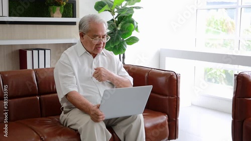 Elderly man sit on couch at home have online consultation on computer with doctor or physician talk on video call use webcam on laptop.