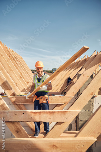 Gladsome man using wood for the roof construction