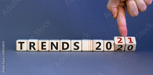 Business concept of planning 2021. Male hand flips wooden cubes and changes the inscription 'TRENDS 2020' to 'TRENDS 2021'. Beautiful grey background, copy space.