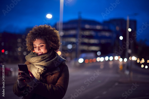 Billede på lærred Woman On City Street At Night Ordering Taxi Using Mobile Phone App