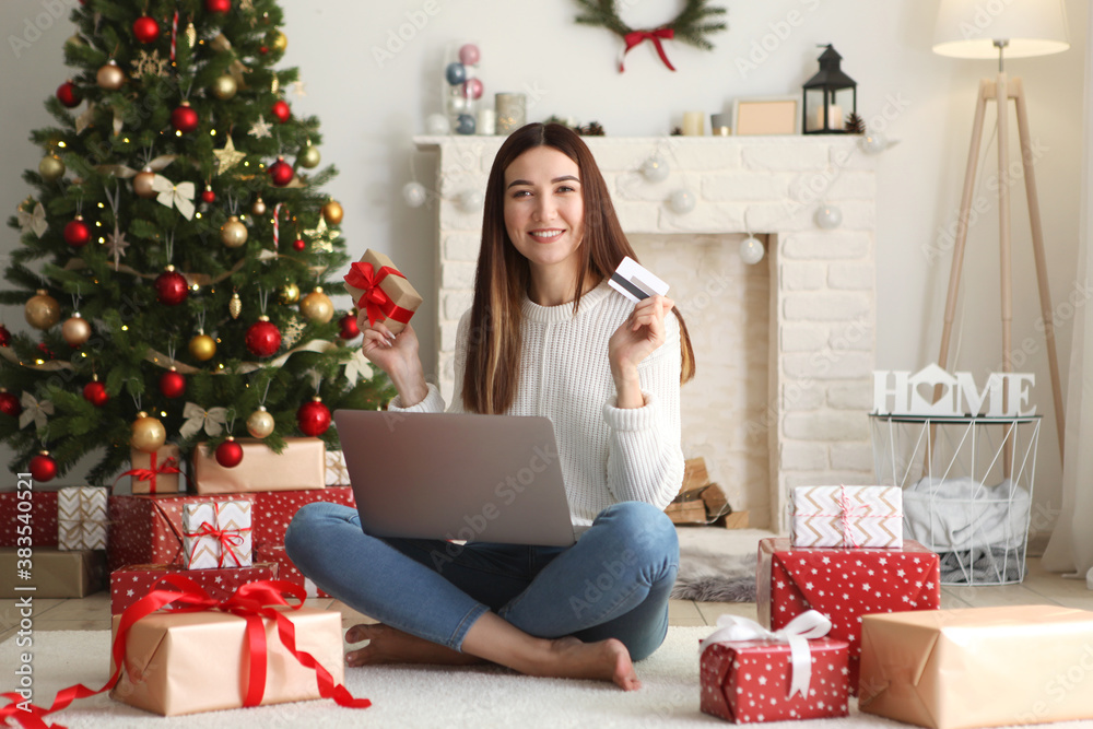 Young beautiful woman is shopping for christmas in festive interior at home Young beautiful woman is shopping for christmas in festive interior at home