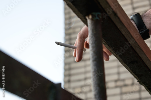 Cigarette in hand close-up on the background of the building