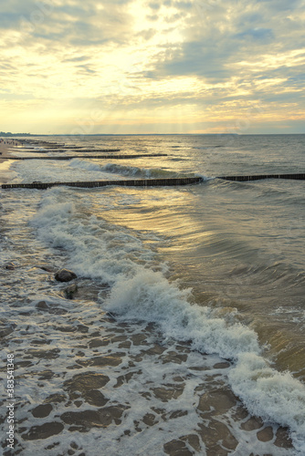 Incoming waves on the Baltic sea beach at sunset.