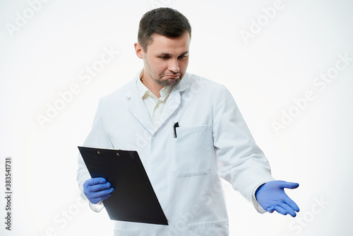 A happy male caucasian doctor in a white lab coat and blue disposable medical gloves is pointing with his hand. A scientist is isolated over white background. photo