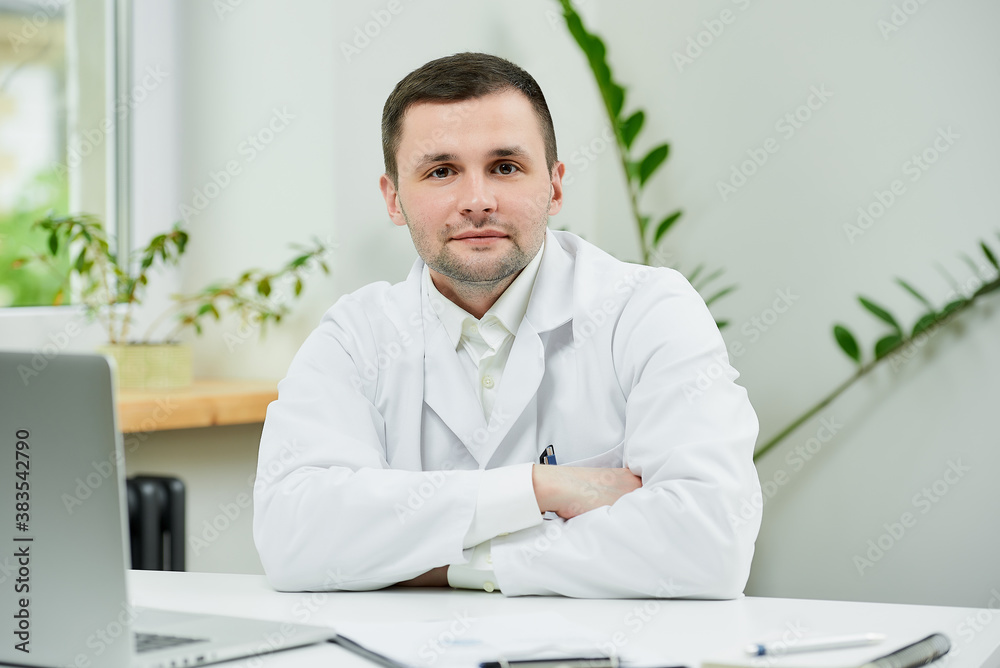 A kind caucasian doctor in a white lab coat is sitting arms crossed and listening in a hospital. A therapist near a laptop is waiting for a patient in a doctor's office. A kind caucasian doctor in a white lab coat is sitting arms crossed and listening in a hospital. A therapist near a laptop is waiting for a patient in a doctor's office.