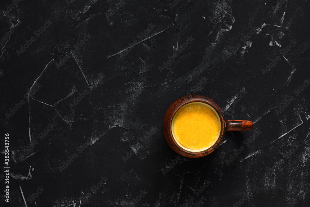 Traditional Indian drink with golden milk turmeric on a black stone background. Top view, copy space. Natural remedy for colds and flu.
