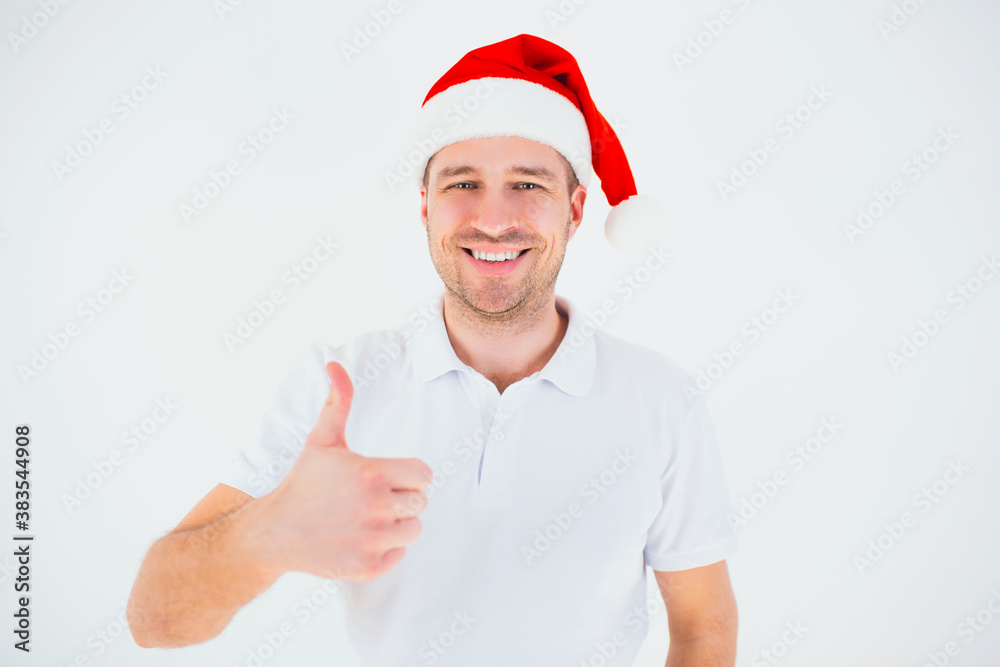 Young man isolated over white background. Guy in festive christmas red hat show big thumb up and smile. Cheerful positive nice guy posing on camera. Christmas time or new year period. Young man isolated over white background. Guy in festive christmas red hat show big thumb up and smile. Cheerful positive nice guy posing on camera. Christmas time or new year period.