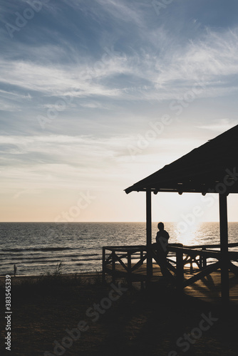  Silueta a contraluz de una mujer mirando la puesta de sol en la playa 