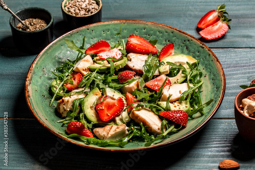 Fresh strawberry salad with arugula, chicken, avocado and strawberries. Plate with a keto diet food. Top view