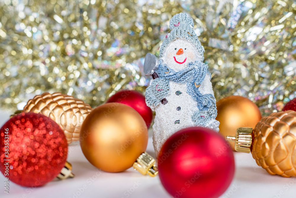 Christmas and new year tree decorations. Christmas composition of little snowman, silver and red balls and glitter garland on red background. Christmas and new year tree decorations. Christmas composition of little snowman, silver and red balls and glitter garland on red background.