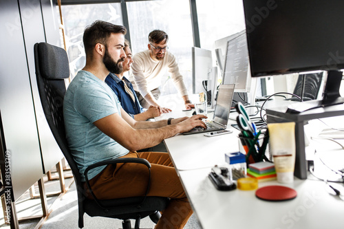 Young programmer sitting at the desk in his office and working .	
 photo