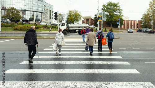 Foto People are walking on a crosswalk on a city street at noon