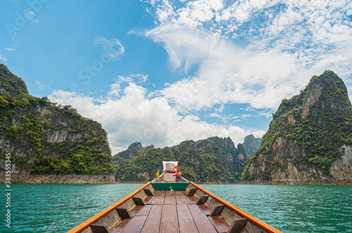 View from a wooden Thai style boat in dam with emerald water and white big stonds. There are many limestones, clear blue sky. Feeling fresh and relax. Ideas for traveling background with copy space. © Pang wrp