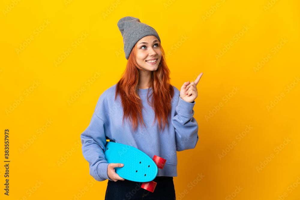 Teenager Russian skater girl isolated on yellow background pointing up a great idea