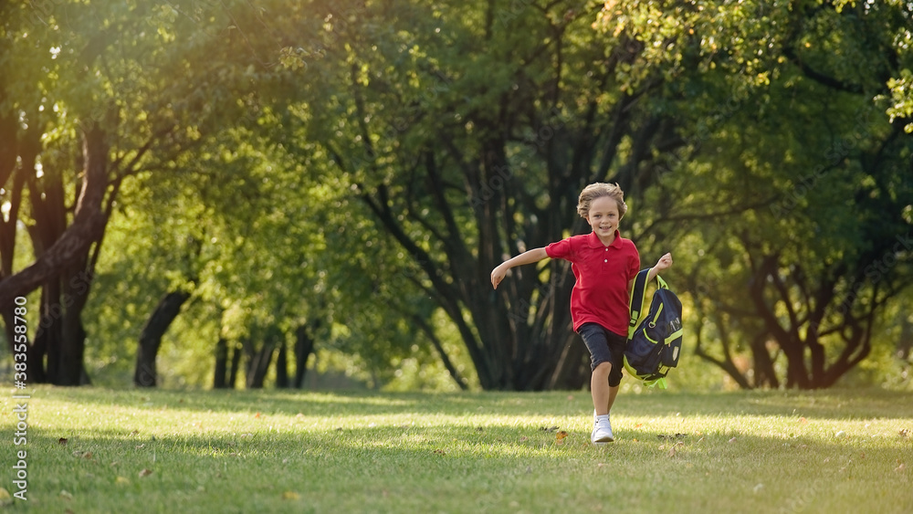 The schoolboy returns from school in a good mood. The boy runs in the park.    