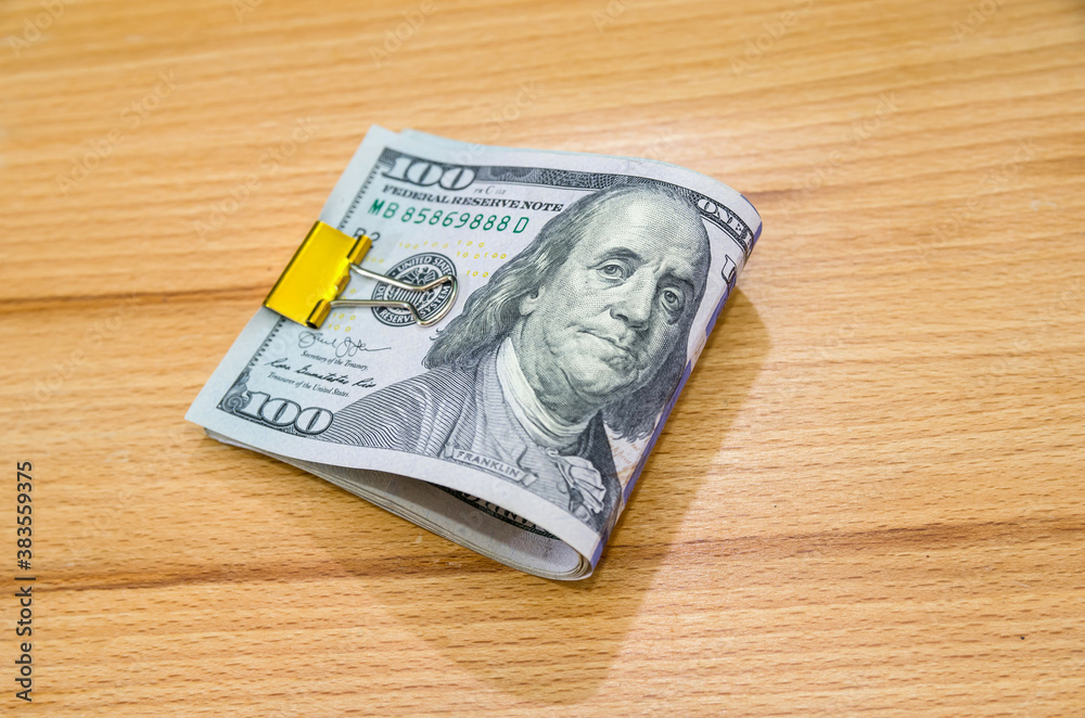 Banknotes of 100 American dollars compressed with a metal clip.